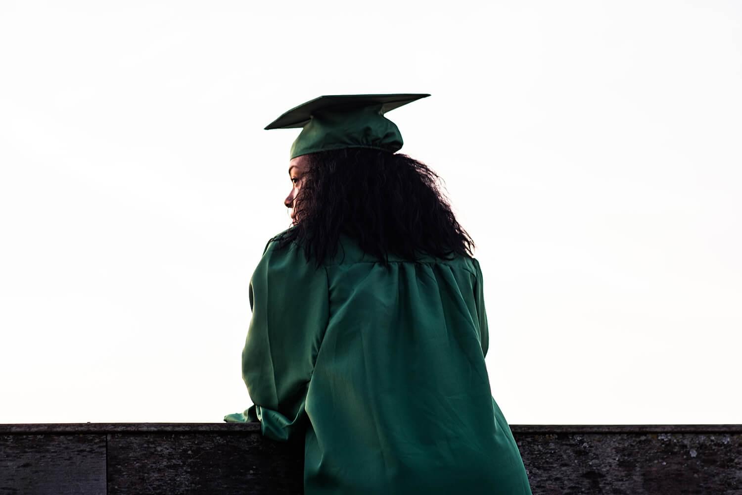 Student in graduation robe watching sunset